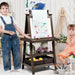 Two kids drawing at a double-sided brown easel with paper roll and storage bins