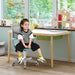 Child sitting on turquoise and gray swivel computer desk chair in a bright playroom with wooden desk and toys