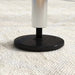 Close-up of adjustable gym bar base with black round foot and threaded steel shaft on textured floor