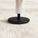 Adjustable steel gymnastics bar base with black circular foot on light carpet