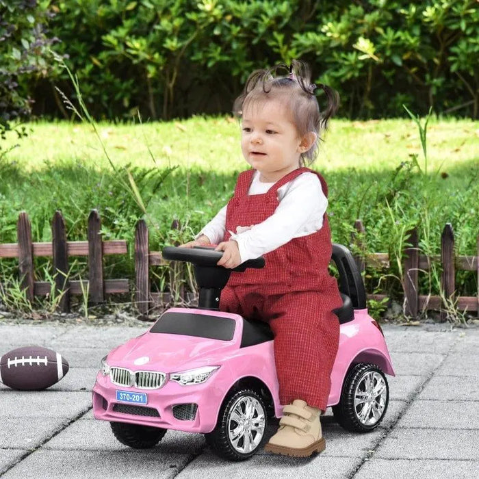 Toddler riding pink foot-to-floor ride-on car toy outdoors, kids sliding car with lights