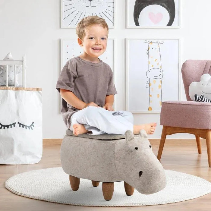 Smiling child sitting on kids hippo storage stool in playful, modern nursery room