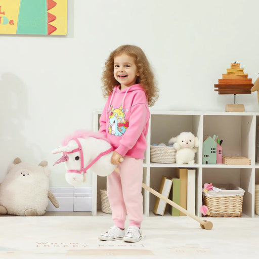 Child in pink outfit playing with a toy horse in a room with toys and books.