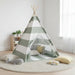Children's teepee with striped design in a room with toys and pillows.