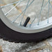 Close-up of a kids scooter wheel with tire valve and silver spokes on pavement