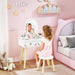 Child playing with a vanity mirror in a pink-themed bedroom