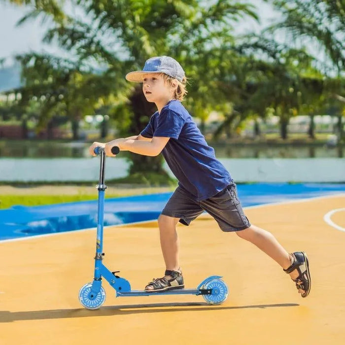 Boy riding blue kids light up music scooter with LED wheels outdoors on playground