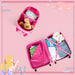 Pink suitcase with compartments filled with toys and clothes on a pink background