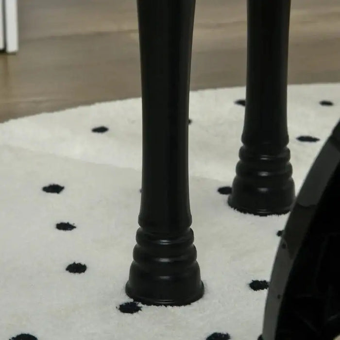 Black piano legs on white rug with black polka dots, close-up view