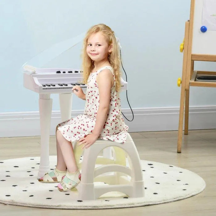 Girl sitting at white kids mini grand piano keyboard on round play mat in a playroom