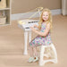 Smiling girl plays white kids mini grand piano with LED lights in cozy room