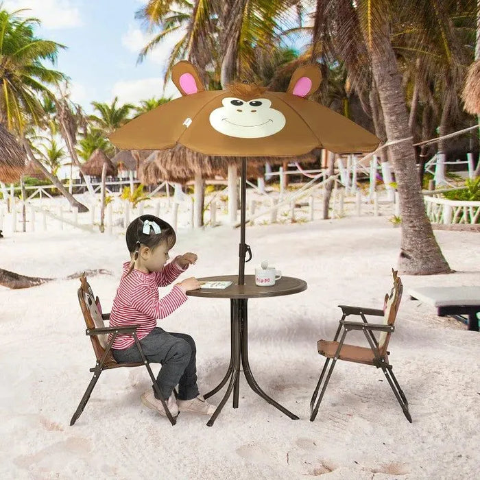 Child using kids monkey garden set with foldable chairs and umbrella on sandy beach