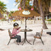 Child using kids monkey garden set with foldable chairs and umbrella on sandy beach