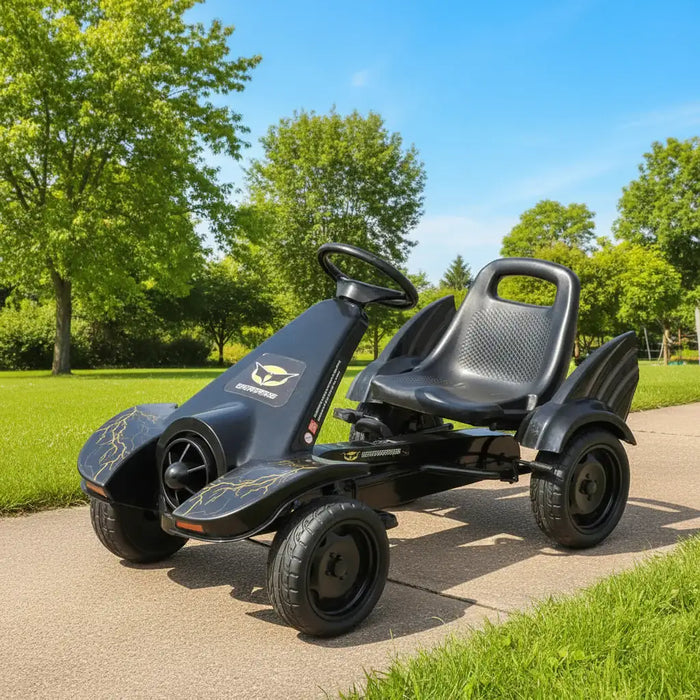 Black pedal go kart for kids on outdoor path with green grass and trees
