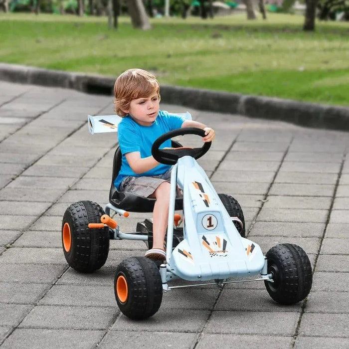 Child riding blue and orange kids pedal go-kart with handbrake outdoors on pavement