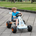 Child riding blue and orange kids pedal go-kart with handbrake outdoors on pavement