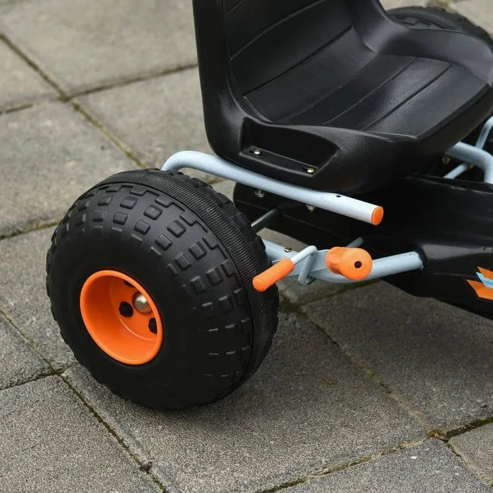 Blue and orange kids pedal go kart with handbrake and gear lever on pavement