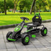Green and black kids pedal go kart with shock-absorbing suspension on paved path outdoors