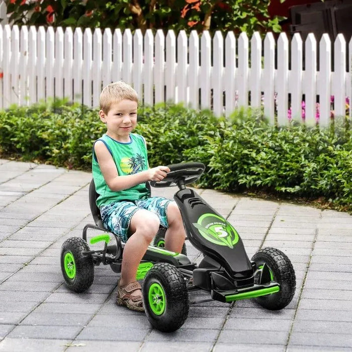 Boy riding green and black kids pedal go-kart with shock absorbing suspension outdoors