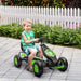 Boy riding green and black kids pedal go-kart with shock absorbing suspension outdoors