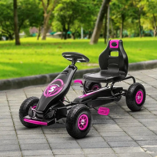 Kids pink and black pedal go kart with handbrake on paved path in park setting