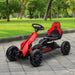 Red and black kids pedal go kart with adjustable seat on paved path in park