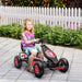 Child riding red and black pedal go-kart with shock-absorbing suspension outdoors