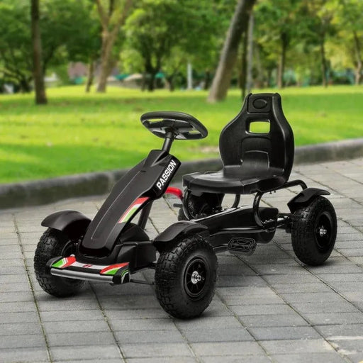 Black kids pedal go-kart with rubber wheels and suspension on park pavement