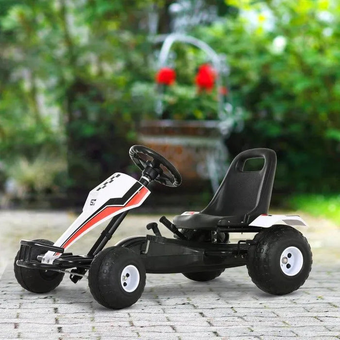 White, red, and black kids pedal go kart with racing stickers on a paved outdoor area