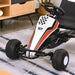 Kids pedal go kart in white, red, and black racing style with stickers, indoors on rug.