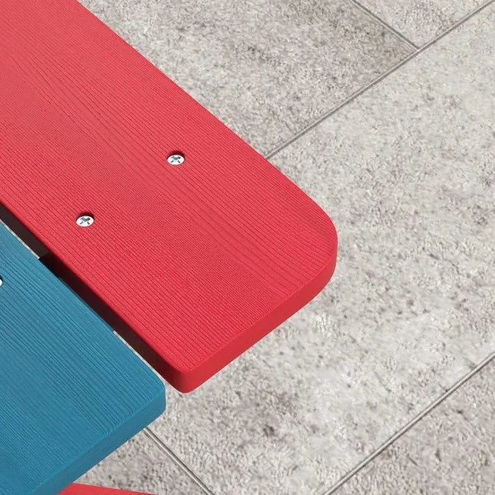 Close-up of colorful kids picnic bench with red and blue fir wood slats on patio tiles