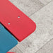 Close-up of colorful kids picnic bench with red and blue fir wood slats on patio tiles