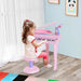 Little girl playing pink kids mini grand piano keyboard set with stool and microphone indoors