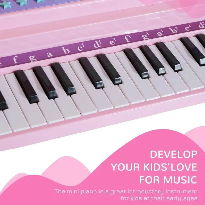 Kids pink 37-key mini piano keyboard close-up with musical notes and white black keys