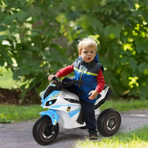 Toddler riding a blue kids police bike toy with lights and music outdoors on a path