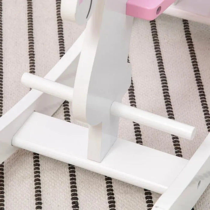 Close-up of kids' pink and white unicorn rocking horse on striped rug
