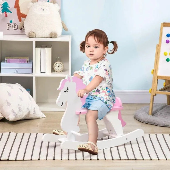 Toddler riding a pink and white unicorn rocking horse in a cozy kids room
