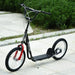 Black kids scooter with big wheels, adjustable handlebar, dual brakes, parked outdoors