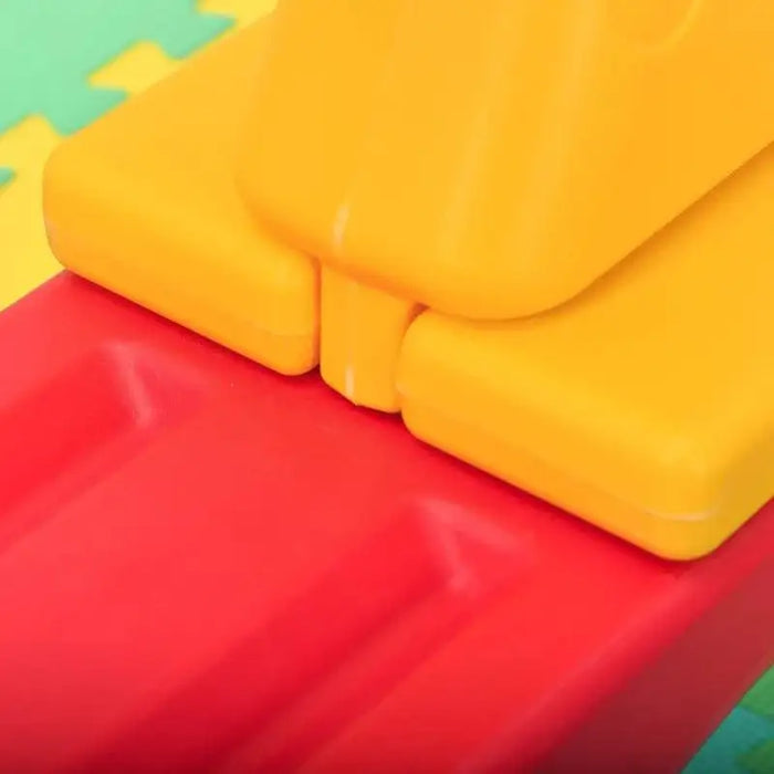 Close-up of yellow and red plastic kids seesaw on foam play mat