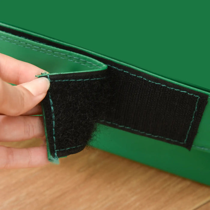 Close-up of a hand opening the black velcro strap on a green soft play foam block