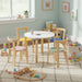 Children's playroom with a round table and colorful chairs, surrounded by toys.
