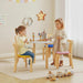 Two young girls playing with toys at a small table in a bright room.