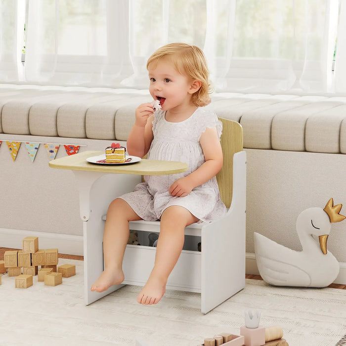 Child sitting on a small chair at a table with a plate of cake, surrounded by toys in a bright room.