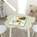 Kids green flower-shaped table and chair set with storybook, plush bear, and plant nearby