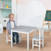 Child sitting at grey and white kids table and chair set in playroom with easel