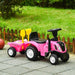 Pink kids' ride-on tractor with trailer and toy tools on patio next to grass yard