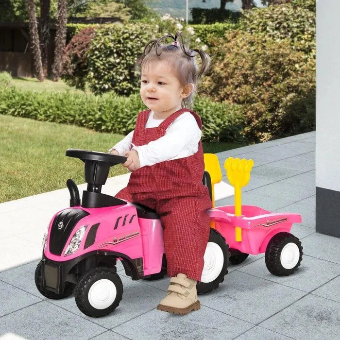 Toddler riding pink kids tractor ride-on toy with trailer outdoors