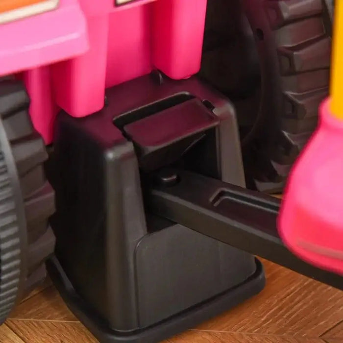 Close-up of pink kids ride-on tractor wheel and cargo box on wood floor