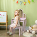 Girl sitting at pink kids vanity table with stool, mirrors, and toys in a playroom