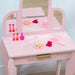 Pink kids vanity table with three mirrors, toy makeup, brush, and hair clip set